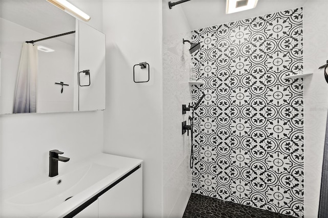 full bathroom featuring tiled shower and vanity