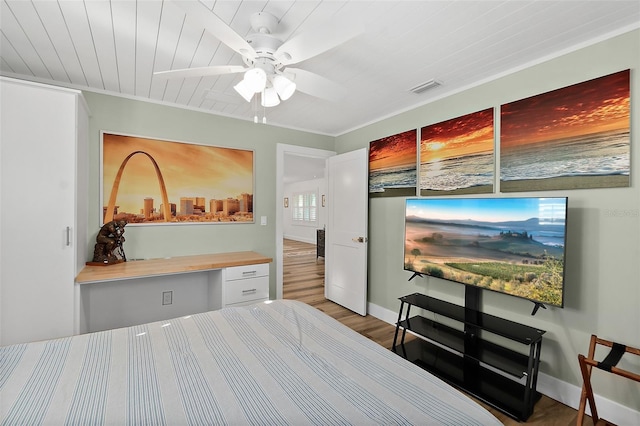 bedroom featuring ceiling fan, built in desk, and wood-type flooring