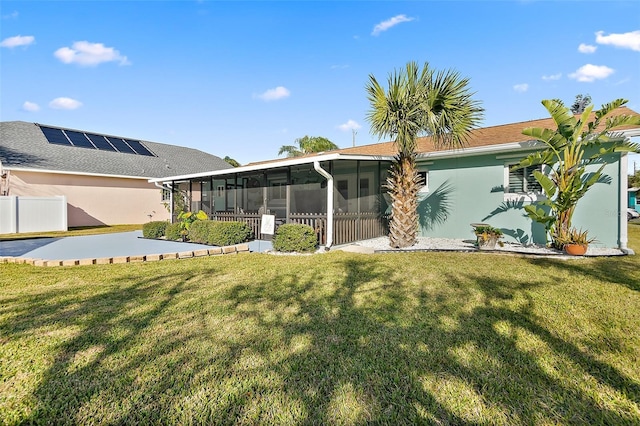 back of house featuring a sunroom, a lawn, and stucco siding