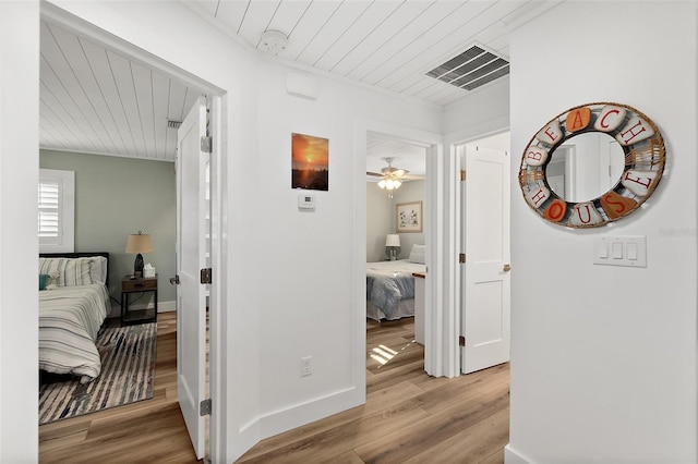 corridor featuring wood ceiling, wood finished floors, visible vents, and baseboards