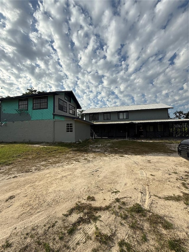 view of property exterior featuring dirt driveway and metal roof