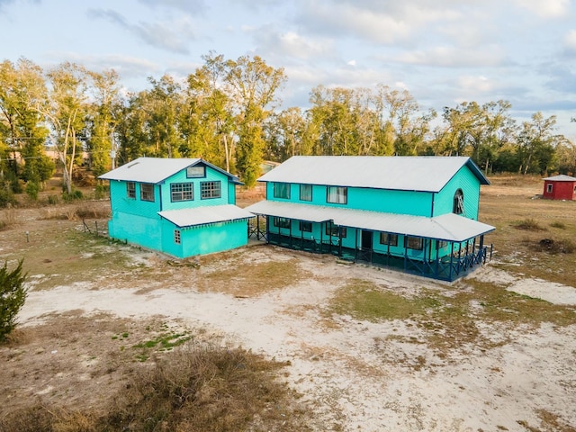 view of front of property featuring view of wooded area and metal roof