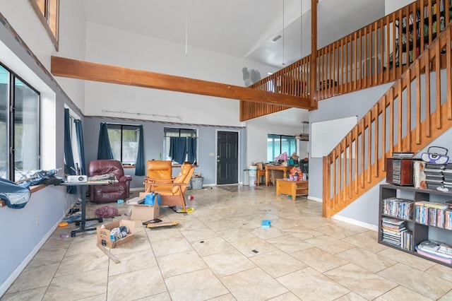 living area featuring a high ceiling, baseboards, and stairs