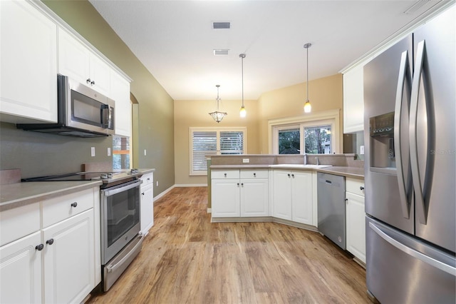 kitchen featuring stainless steel appliances, visible vents, white cabinets, light countertops, and decorative light fixtures