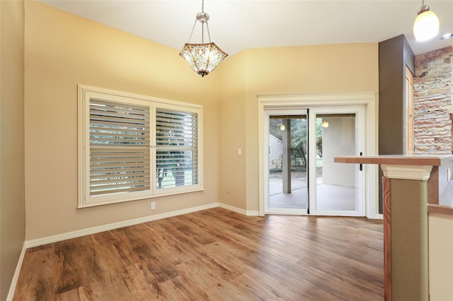 interior space featuring plenty of natural light, baseboards, a chandelier, and wood finished floors