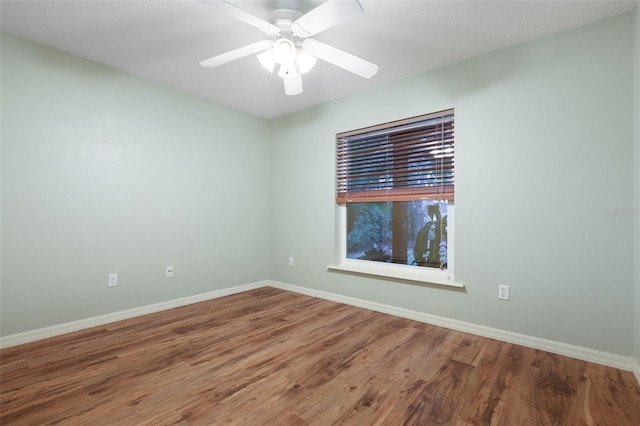 empty room with ceiling fan, wood finished floors, and baseboards