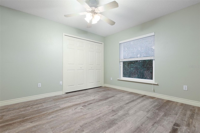 unfurnished bedroom featuring a ceiling fan, light wood-style flooring, baseboards, and a closet