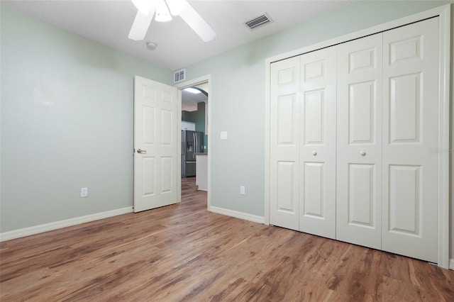 unfurnished bedroom with arched walkways, stainless steel fridge with ice dispenser, visible vents, light wood-type flooring, and baseboards