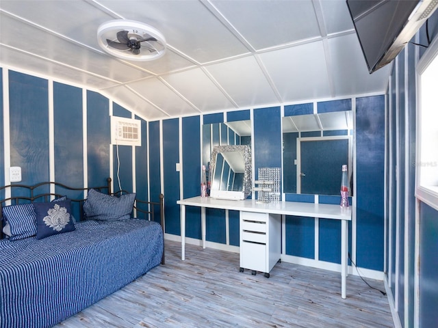 bedroom featuring a wall unit AC, vaulted ceiling, and wood finished floors