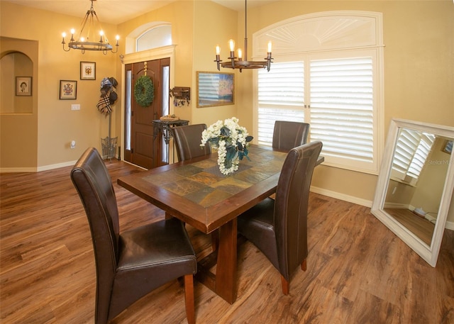 dining space with baseboards, a chandelier, and wood finished floors