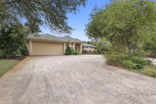 ranch-style home with decorative driveway, an attached garage, and stucco siding