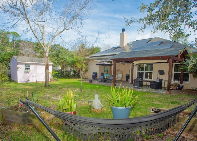 rear view of house with a patio, an outbuilding, a yard, a shed, and stucco siding