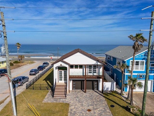 view of front of house featuring a garage, a water view, and a front lawn