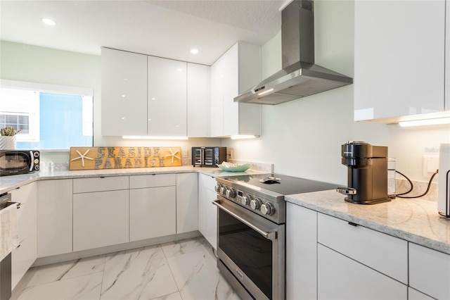 kitchen with light stone counters, wall chimney exhaust hood, high end stove, and white cabinets