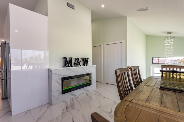 dining space with a tiled fireplace, vaulted ceiling, and plenty of natural light