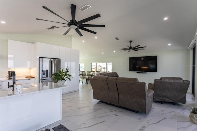 living room featuring vaulted ceiling, sink, and ceiling fan