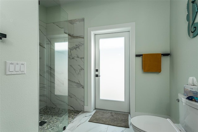 bathroom with a tile shower and toilet