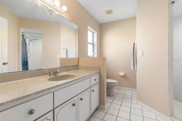 bathroom with vanity, tile patterned flooring, toilet, and a tile shower