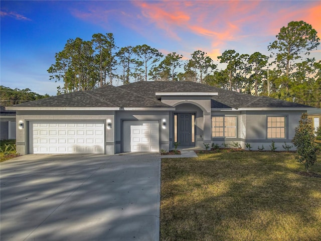 ranch-style house featuring a garage and a lawn