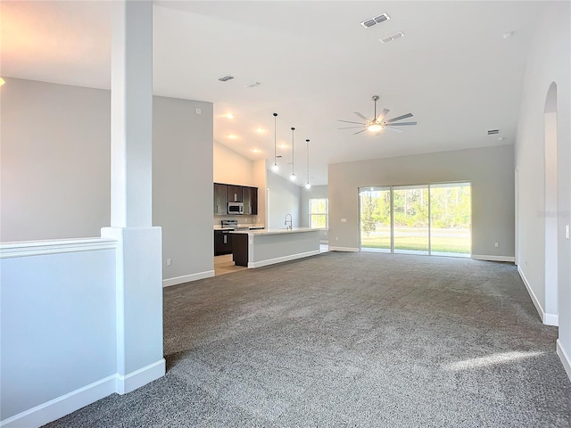 unfurnished living room featuring ceiling fan, carpet, sink, and high vaulted ceiling