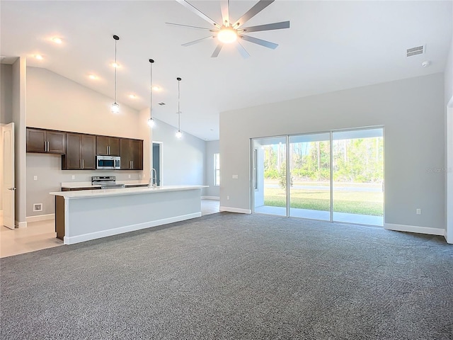 kitchen featuring high vaulted ceiling, dark brown cabinets, stainless steel appliances, and a center island with sink