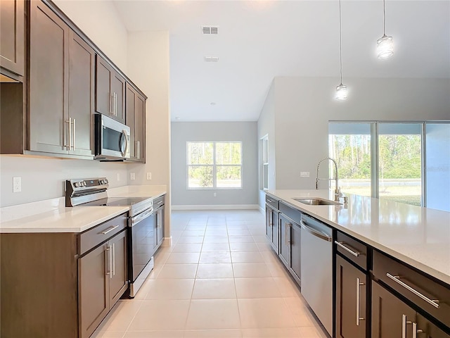 kitchen with light tile patterned flooring, sink, decorative light fixtures, dark brown cabinets, and appliances with stainless steel finishes