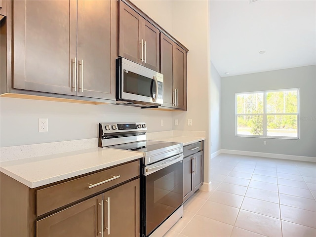 kitchen featuring stainless steel appliances, light tile patterned floors, and light stone counters