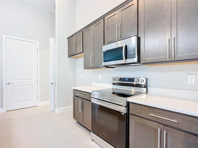 kitchen featuring light stone countertops, stainless steel appliances, and light tile patterned flooring