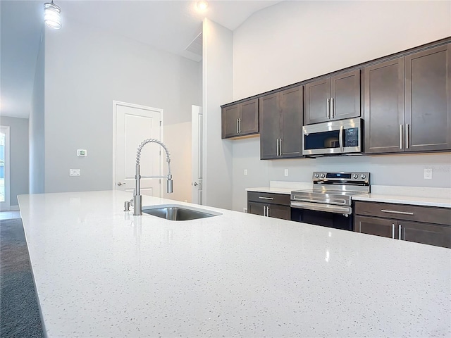 kitchen with sink, stainless steel appliances, high vaulted ceiling, dark brown cabinetry, and light stone countertops