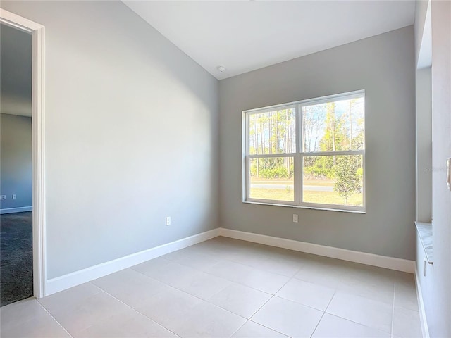 unfurnished room with vaulted ceiling and light tile patterned floors