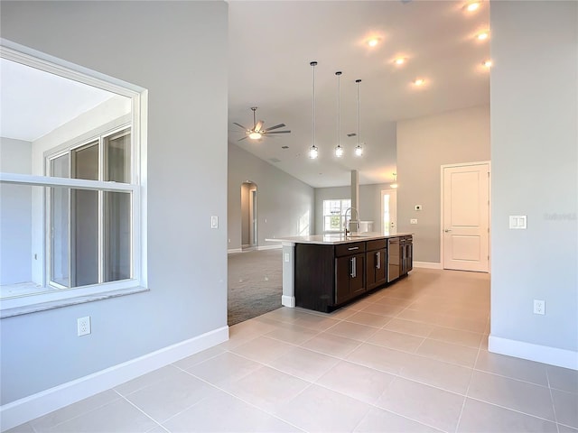 kitchen featuring dark brown cabinetry, sink, light tile patterned floors, and ceiling fan