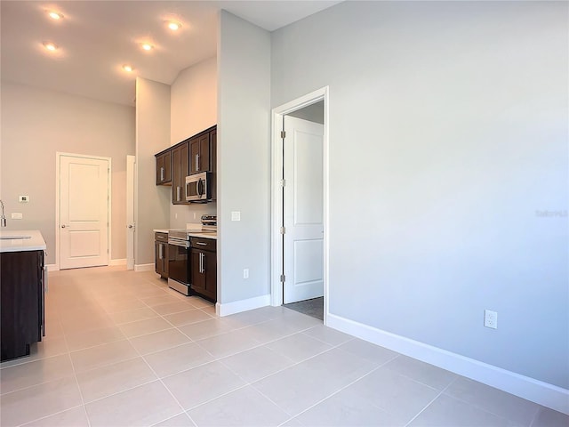 kitchen with appliances with stainless steel finishes, dark brown cabinets, sink, and light tile patterned floors