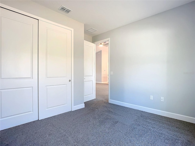 unfurnished bedroom featuring a closet and dark colored carpet