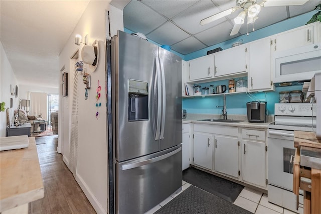 kitchen featuring white appliances, a drop ceiling, sink, and white cabinets