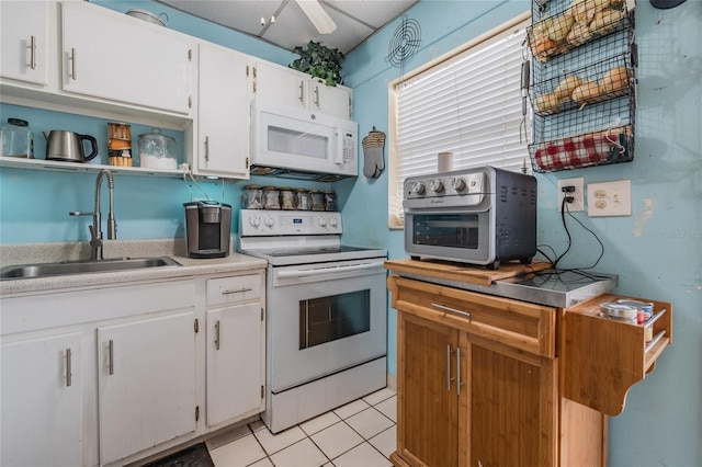 kitchen with white appliances, light tile patterned floors, sink, and white cabinets