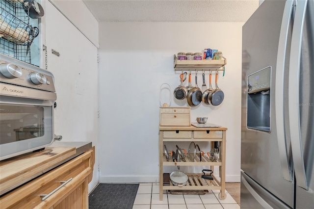 kitchen with stainless steel fridge, oven, a textured ceiling, and light tile patterned floors