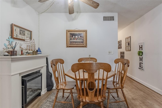 dining space featuring ceiling fan, light hardwood / wood-style floors, and a textured ceiling