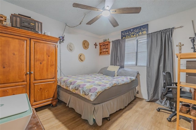 bedroom with ceiling fan, light hardwood / wood-style floors, and a textured ceiling