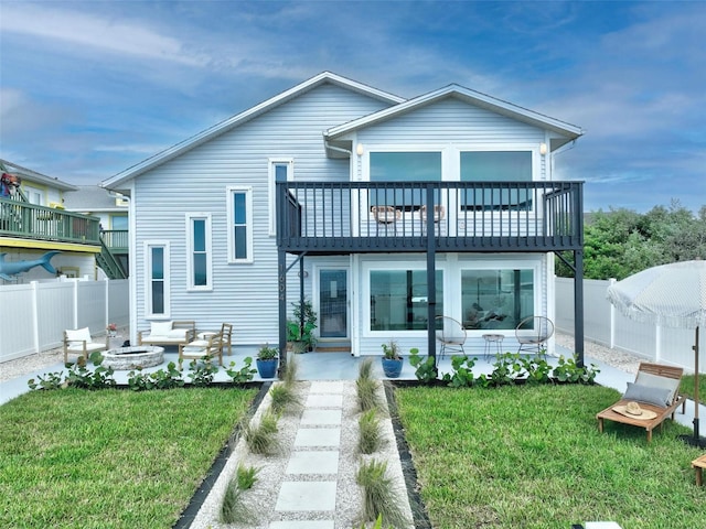 rear view of property featuring a balcony and a yard