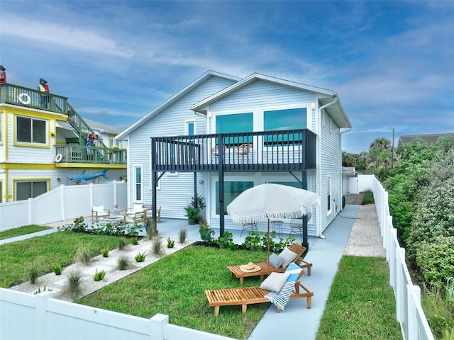 rear view of house featuring a balcony, a yard, and a patio area