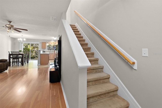 staircase with a notable chandelier, hardwood / wood-style flooring, and a textured ceiling