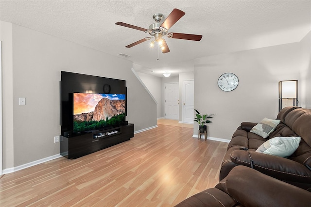 living room featuring ceiling fan, a textured ceiling, and light wood-type flooring