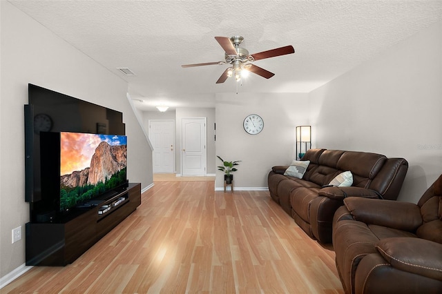 living room with ceiling fan, light hardwood / wood-style flooring, and a textured ceiling