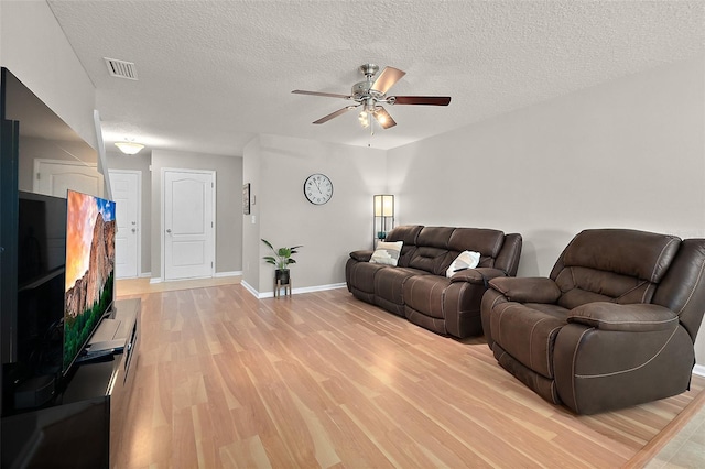 living room with ceiling fan, a textured ceiling, and light hardwood / wood-style floors