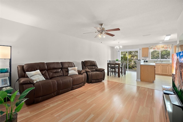 living room featuring sink, ceiling fan with notable chandelier, and light hardwood / wood-style floors