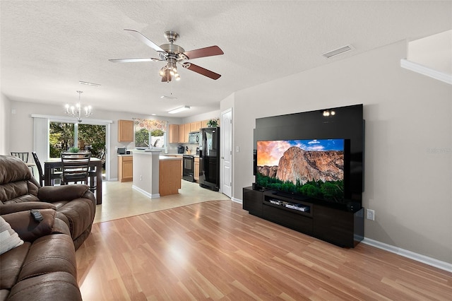 living room featuring ceiling fan with notable chandelier, a textured ceiling, and light wood-type flooring