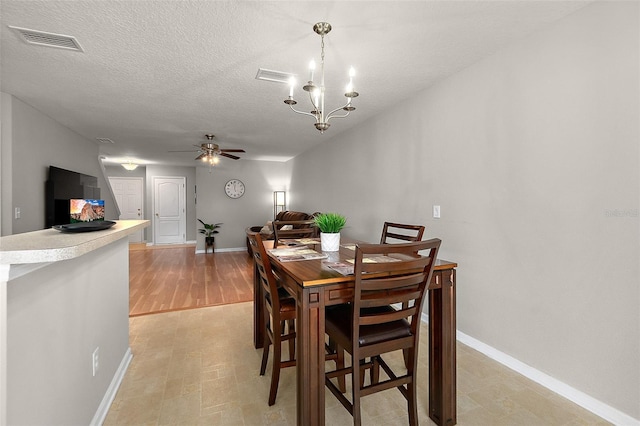 dining space with ceiling fan with notable chandelier and a textured ceiling