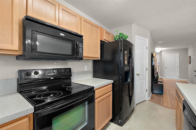 kitchen featuring light brown cabinetry, a textured ceiling, and black appliances