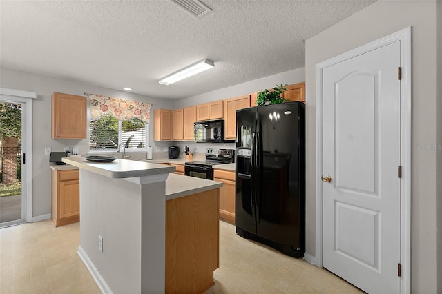 kitchen with light brown cabinetry, black appliances, a center island, and a textured ceiling