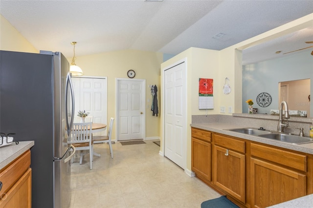 kitchen featuring hanging light fixtures, vaulted ceiling, sink, and stainless steel fridge